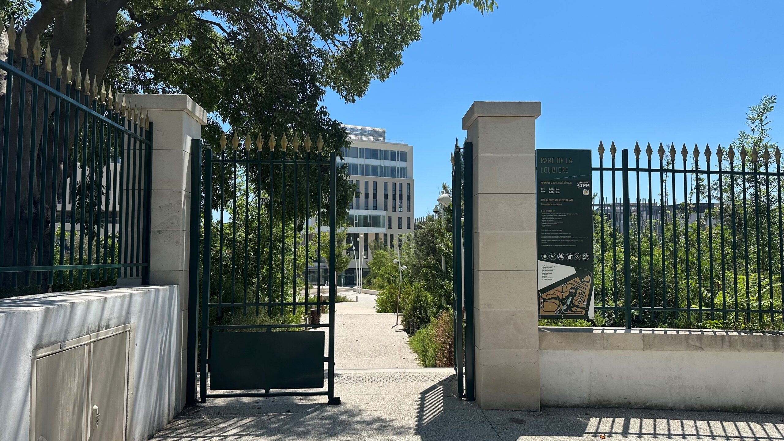 Grille d'entrée du parc voisin du centre d'imagerie, avec un panneau d'information